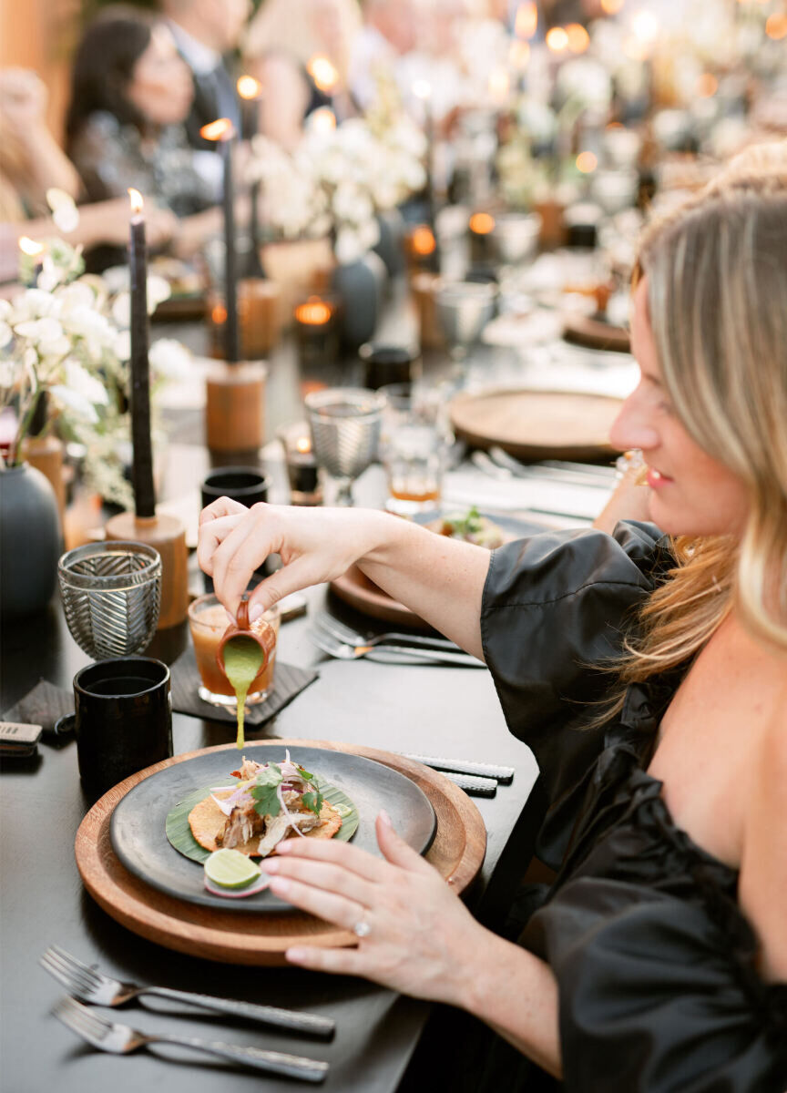 A guest pours sauce on her taco during a Mexican wedding reception.
