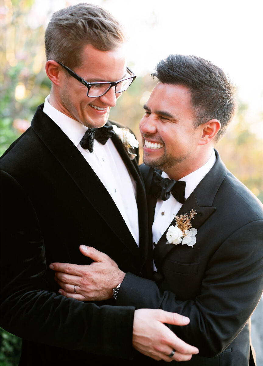 A pair of newlyweds embrace one another and smile wildly.