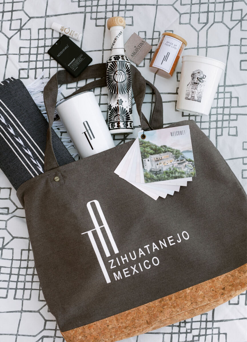 A wedding welcome bag filled with local amenities such as tequila and spices, as well as other items branded with the couple's monogram.