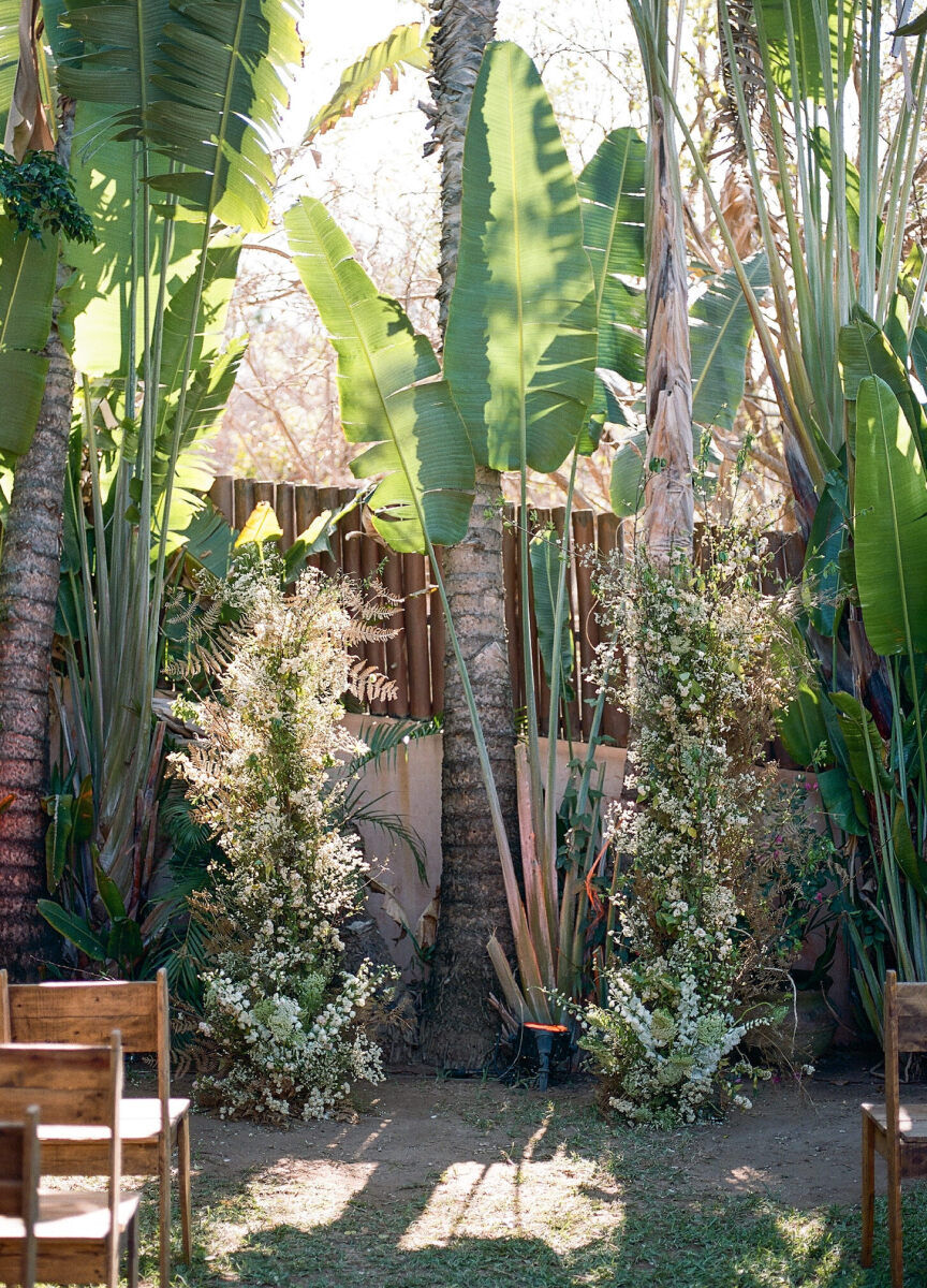 A pair of tall floral arrangements accented the outdoor ceremony setting, which was surrounded by tropical foliage and palm trees.