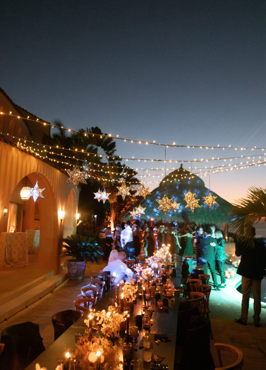 Twinkle lights and star lanterns hang over the outdoor reception space at this bohemian wedding in Mexico.