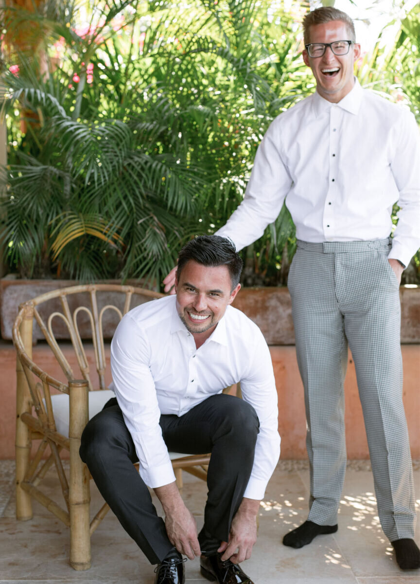 Two grooms smile as they get ready together ahead of their bohemian wedding in Mexico.