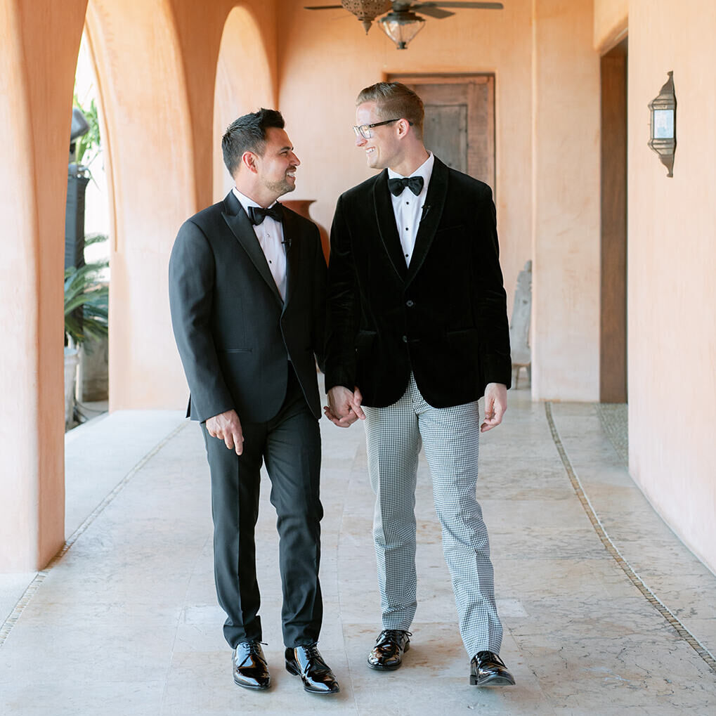 Wedding couple walking hand in hand in front of their Bohemian wedding venue in Mexico.