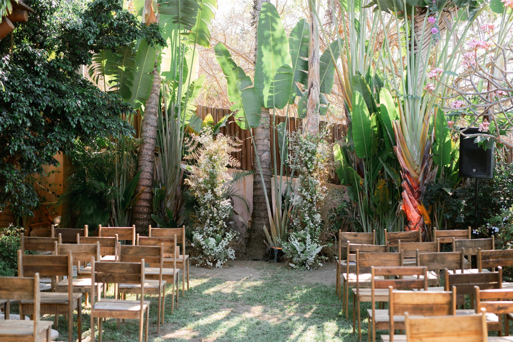 A pair of tall floral arrangements accented the outdoor ceremony setting, which was surrounded by tropical foliage and palm trees.
