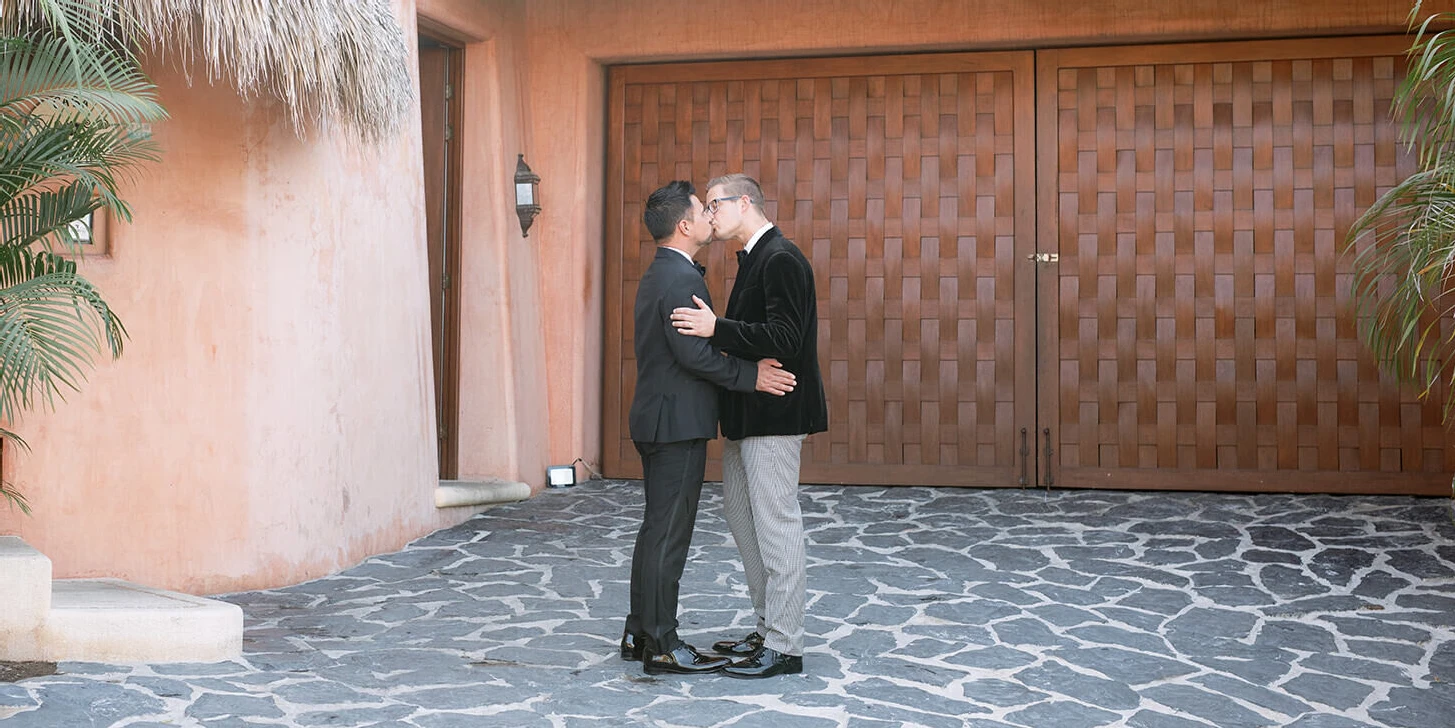 Wedding couple kissing in front of their bohemian wedding venue in Mexico.